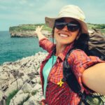 Happy woman backpacker traveler take a selfie photo on amazing ocean coast