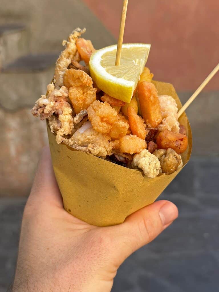 A,Hand,Holds,A,Cone,Of,Fritto,Misto,,Which,Is