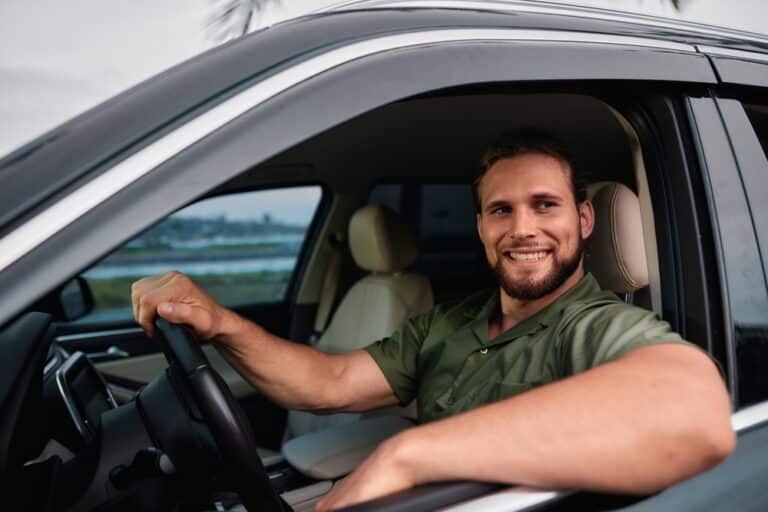 Smiling man driving a car with natural background and palm trees
