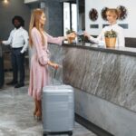 Young,Attractive,Woman,With,Packed,Suitcase,Standing,In,Hotel,Lobby